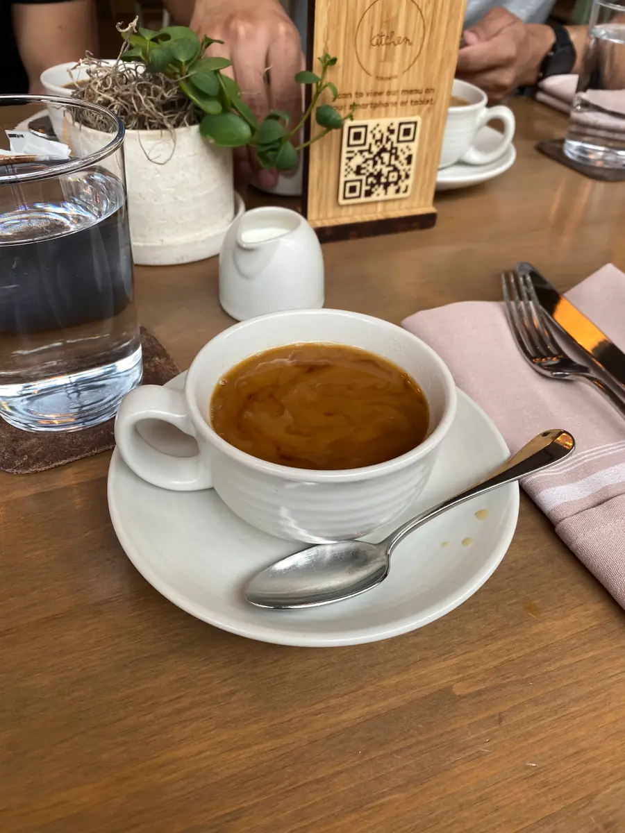 A cafe table with an espresso and a QR code stand
