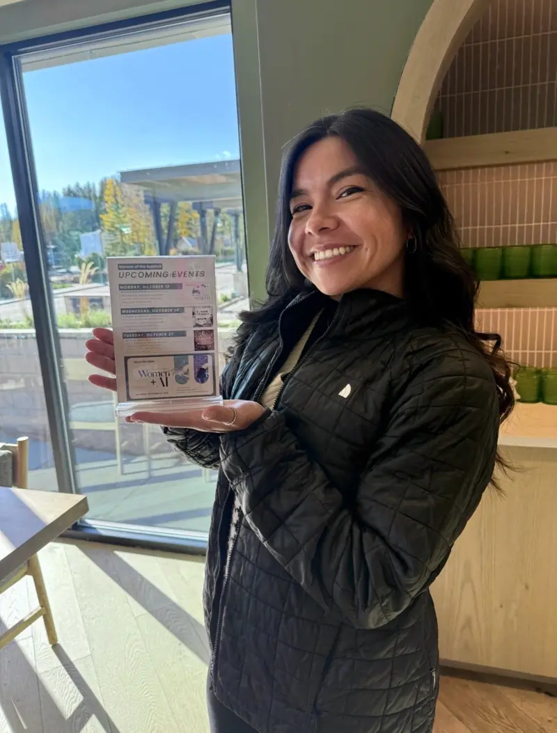Samantha Quinones holding the Women of the Summit upcoming events sign with the Women + AI save the date
